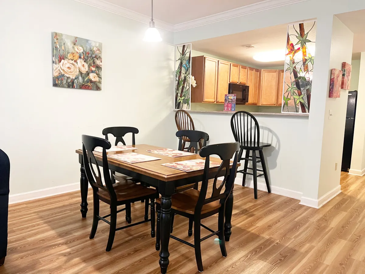 A dining area centered around a welcoming table, complemented by artwork and a kitchen bar, creates a space designed for shared meals and gatherings.