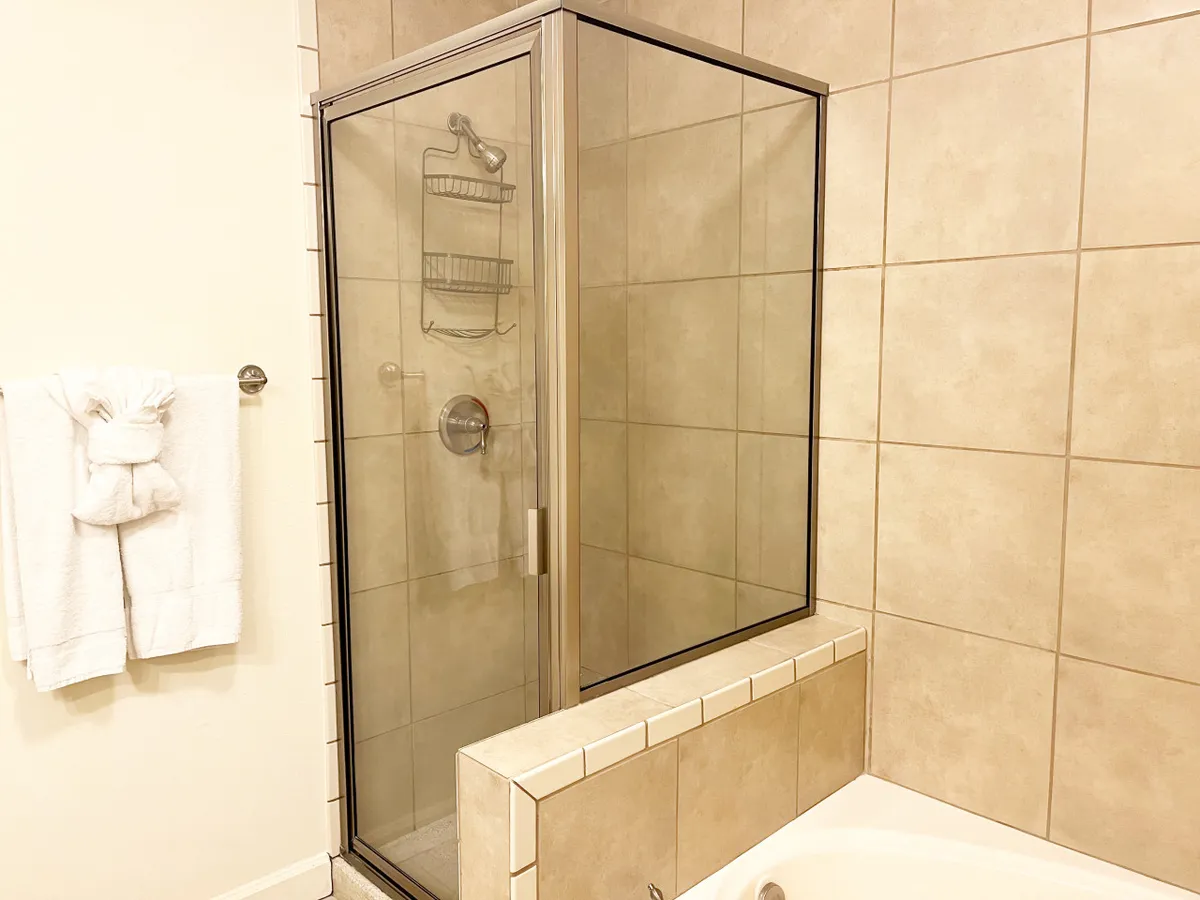 A sophisticated bathroom with a glass shower enclosure, a deep bathtub, and a towel rack adorned with plush white towels. The calm, neutral tones and tasteful decor create an inviting, serene environment reminiscent of a high-end spa.