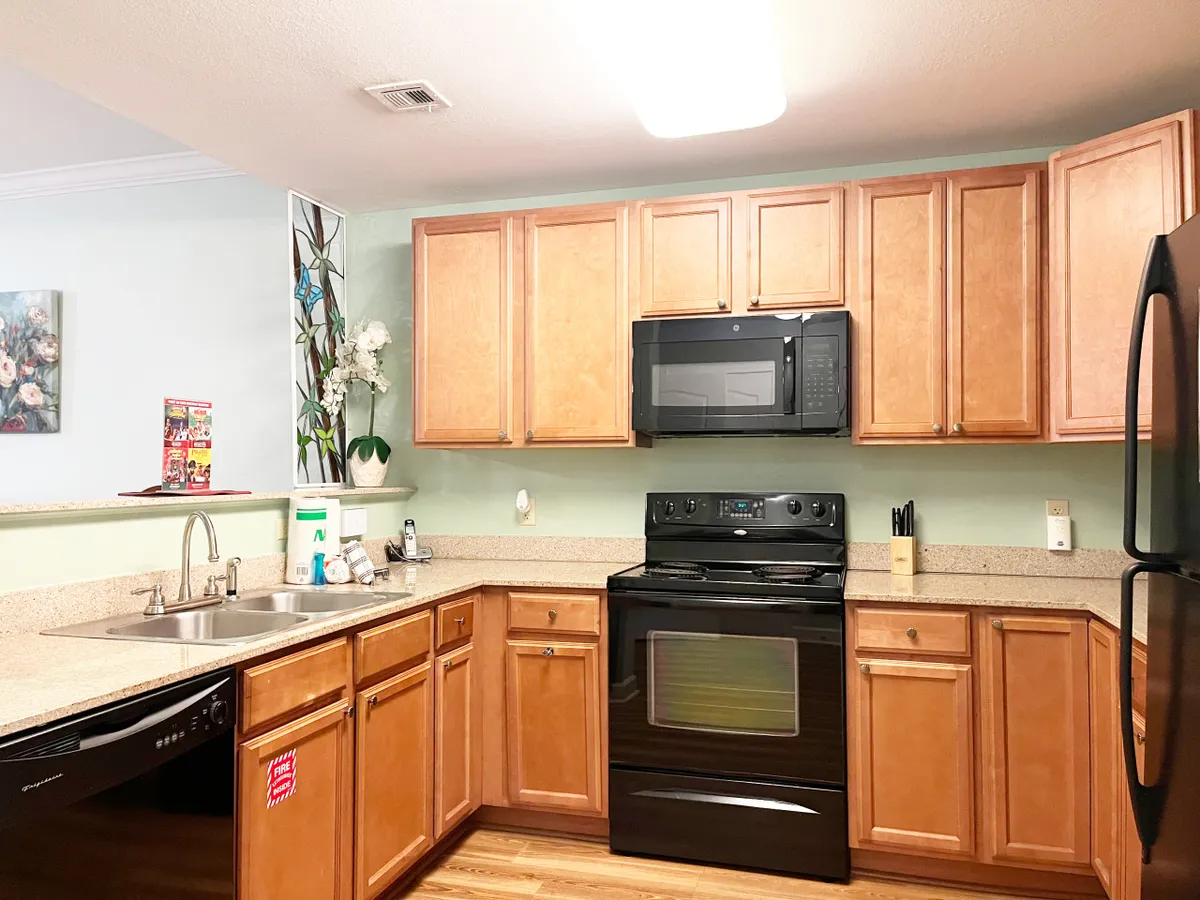 A bright, open kitchen with warm cabinetry, a stove, sink, and decorative elements. The space exudes warmth and is set up for cooking, entertaining, or enjoying family meals.
