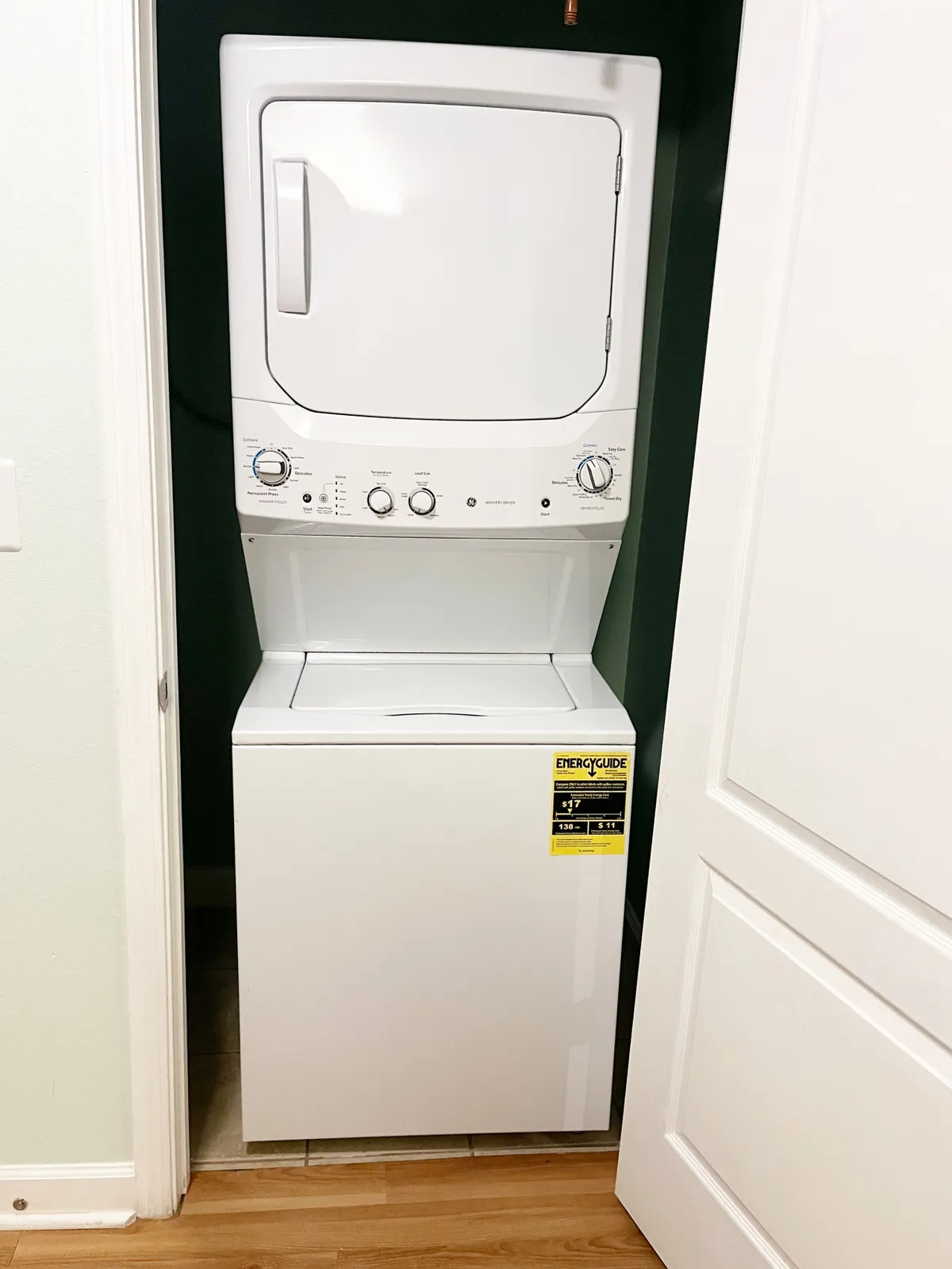 A stacked washer and dryer are neatly tucked into a corner, showing a practical and modern laundry solution. The energy guide sticker and organized presentation emphasize efficiency and convenience—an essential amenity for extended family stays or group getaways.