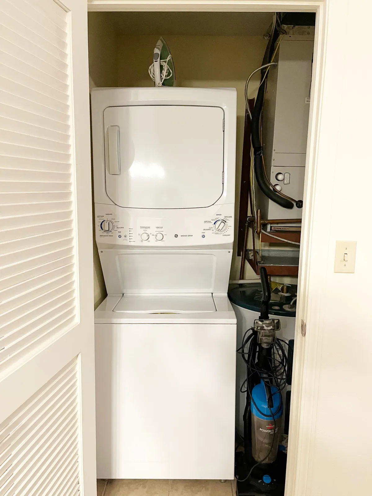A utility area featuring a washer, dryer, iron, and vacuum cleaner, all neatly arranged for easy guest access. The space is practical and well-maintained, emphasizing self-sufficiency during long or short stays.